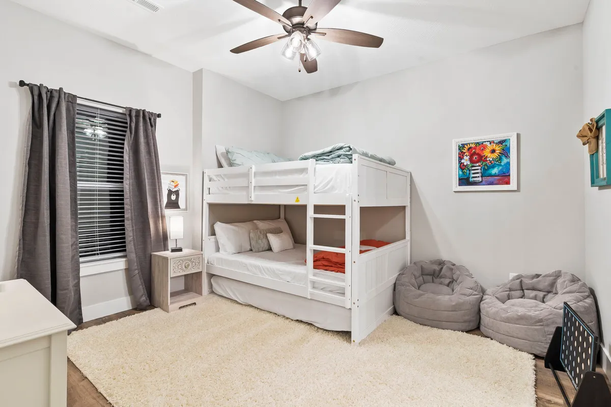 A cheerful, child-friendly bedroom featuring a full-over-full bunk bed, soft bean bag chairs, a floor lamp for reading, and playful wall art. The space looks inviting for both sleep and play, perfectly tailored for kids or siblings.