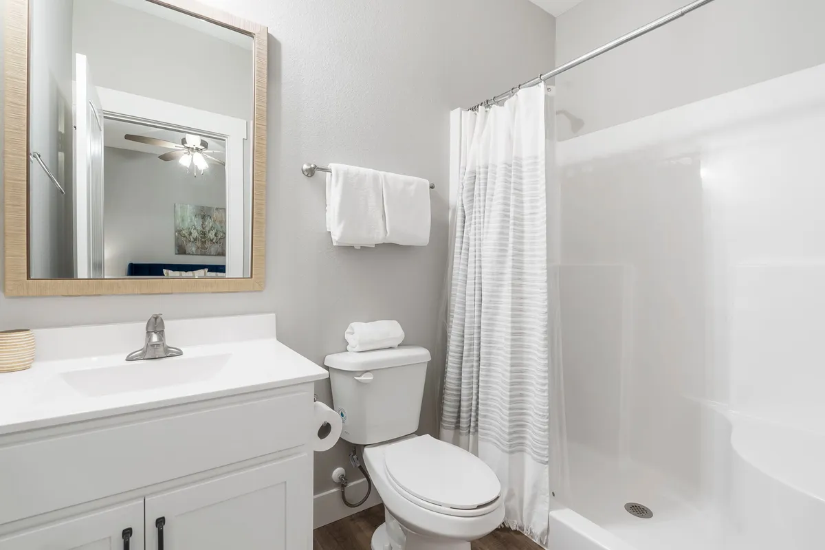 An elegant ensuite bathroom with a modern vanity, large mirror, glass shower stall, and tranquil lighting. The layout is spacious and clean, ideal for personal grooming and relaxation.
